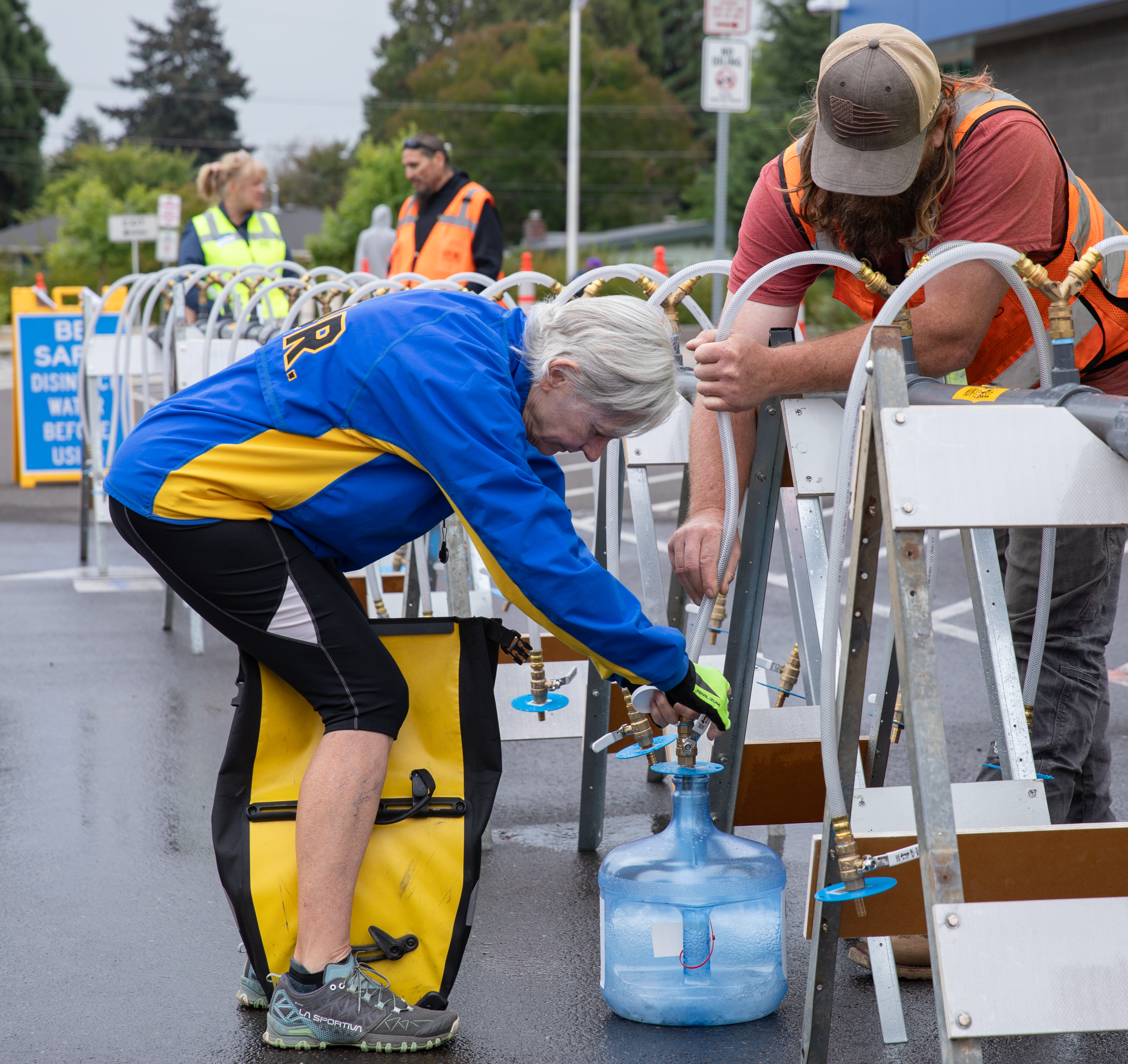 EWEB staff help community member fill emergecy water container at Emergency Water Station
