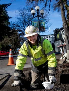 EWEB staff smiling at camera while standing in hole in street