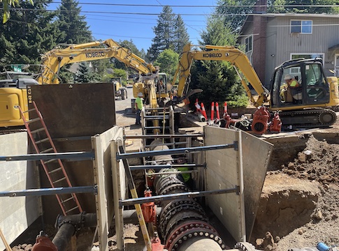 Two backhoe machines and open pipeline infrastructure along E. 40th for pipeline repalcement