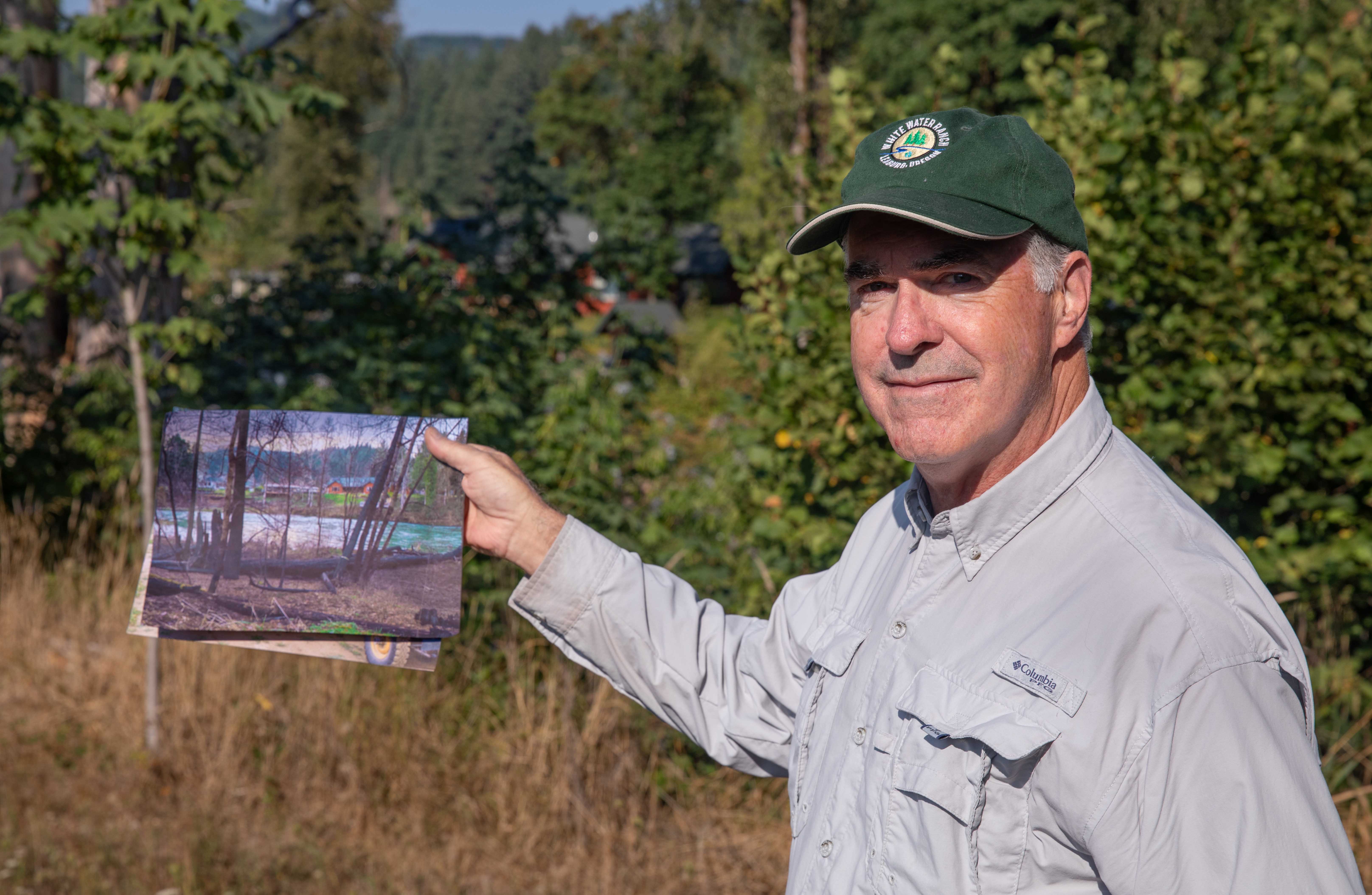 Jim Russell holds a photo showing the regeneration along the burned riverside four years ago compared to today.
